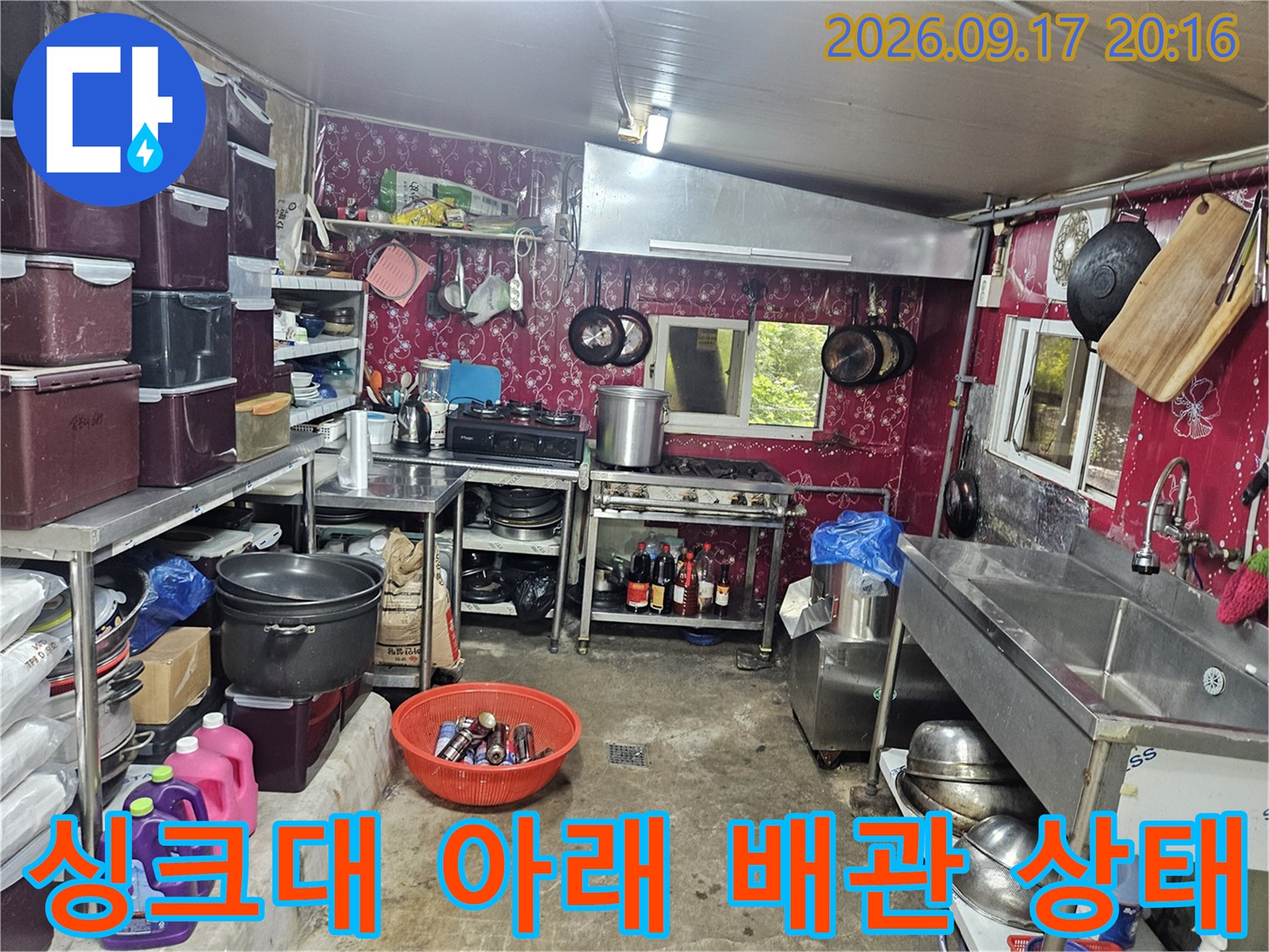주방 싱크대 하단부의 복잡한 배관 및 수납 공간 모습